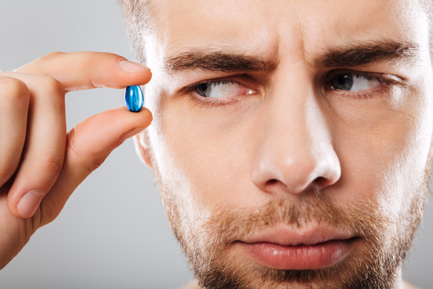 Man skeptically examining ED pill, illustrating pill fatigue with erectile dysfunction medication